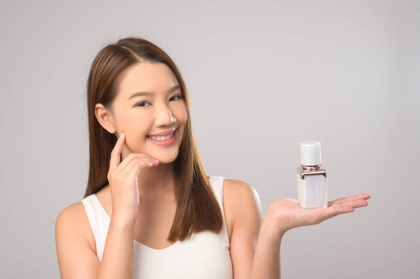 A Portrait of beautiful asian woman holding moisturizer cream over white background studio, skin care and beauty concept - Photo, Image
