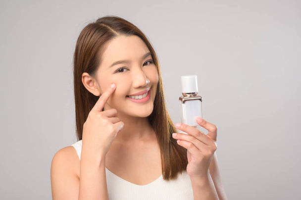 A Portrait of beautiful asian woman holding moisturizer cream over white background studio, skin care and beauty concept - Fotó, kép