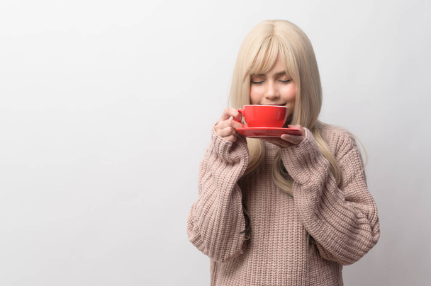 Portrait of Caucasian young woman wearing sweater drinking coffee over white background - Fotoğraf, Görsel