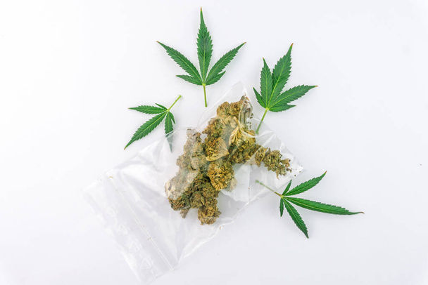 Sac avec bourgeons de fleurs de cannabis et feuilles de marijuana isolées sur blanc - Photo, image