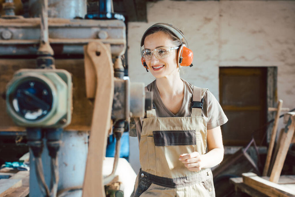 Женщина-плотник в традиционной столярной промышленности регулирует машину строгальщика вручную - Фото, изображение