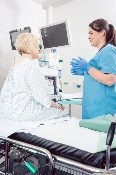 Enfermera explicando procedimiento al paciente en cirugía hospitalaria para aliviar la ansiedad - Foto, Imagen