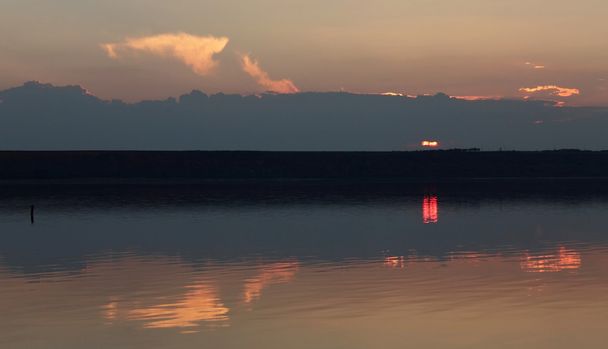 Auringonlasku ja heijastus peilipinnassa
 - Valokuva, kuva