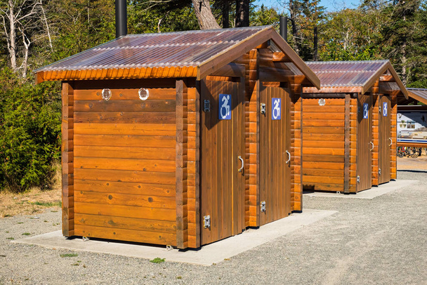 Public toilet in park. Sunny summer day Wooden restroom or toilet building in remote forest in park. Bathrooms or WC. Nobody, street photo, selective focus - Photo, Image