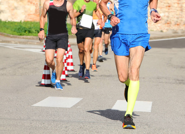 athletic runner with long muscular legs during the foot race in the city - Photo, Image