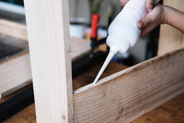 Woodworking operators are using glue to put together the wood parts to assemble and build a wooden table for their customers - Fotoğraf, Görsel