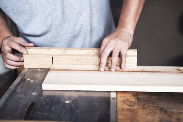 Houtbeoefenaars gebruiken zaagbladen om stukken hout te zagen om houten tafels te monteren en te bouwen voor hun klanten. - Foto, afbeelding