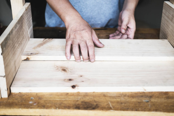 Плотник измеряет доски для сборки деталей и строит деревянный стол для заказчика - Фото, изображение
