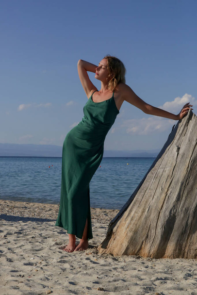 Beautiful young model in camisole emerald green silk satin long dress, fashion summer portrait on the beach - Photo, Image