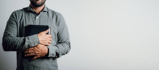 Стоящий мужчина держит и обнимает библию на груди. Копирование пространства - Фото, изображение