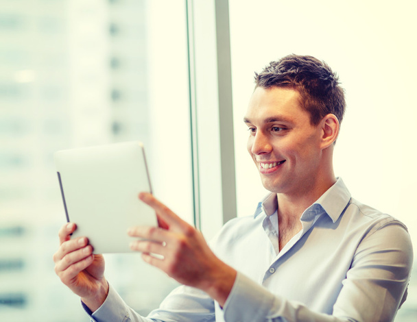 smiling businessman with tablet pc in office - Foto, Bild