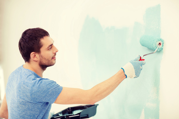 smiling man painting wall at home - 写真・画像