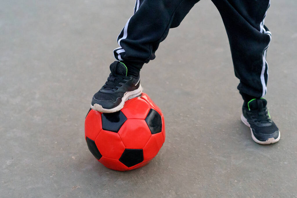 サッカーボールの上に男の子の足のクローズアップ. - 写真・画像
