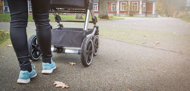 Kinderwagen mit Säugling, Beinen und Rädern aus nächster Nähe. - Foto, Bild