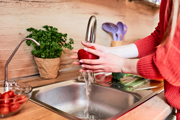 Zbliżenie dziewczęcych rąk myjących warzywa w kuchni pod kranem. Przygotowanie warzyw do gotowania.  - Zdjęcie, obraz