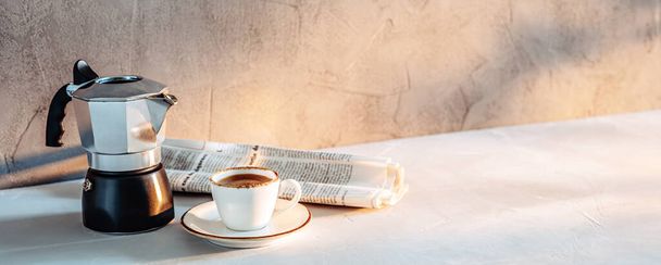 Чашка еспресо, кавоварка і газета в ранковому сонячному світлі
. - Фото, зображення