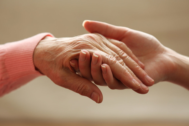 Old and young holding hands on light background, closeup - Valokuva, kuva