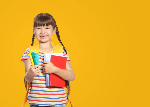 Cute girl with school stationery on yellow background, space for text - Fotografie, Obrázek