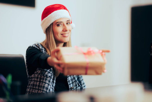 Businesswoman Wearing a Santa hat Giving a Present to her Coworker  - Fotografie, Obrázek