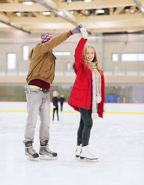 happy couple holding hands on skating rink - 写真・画像