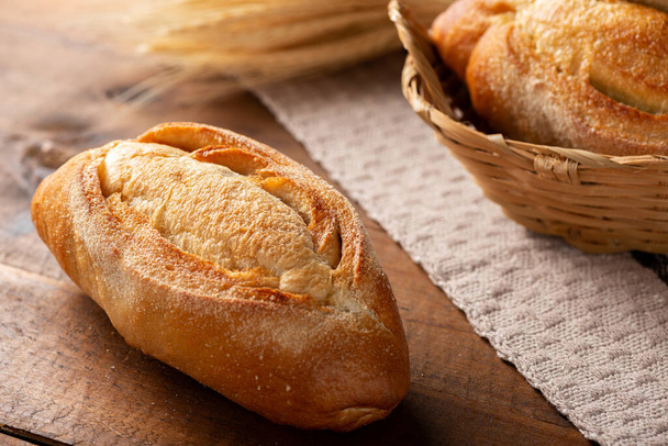 Italian bread on rustic wood with wheat branches. - Photo, Image