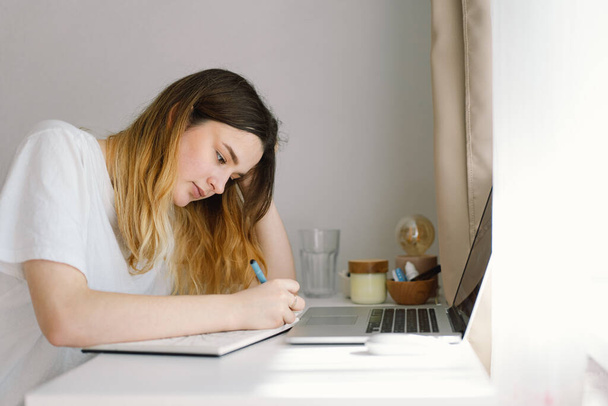 A teenage girl is drawing or doing homework in the bedroom. A teenager studies at home. Back to school - Fotó, kép