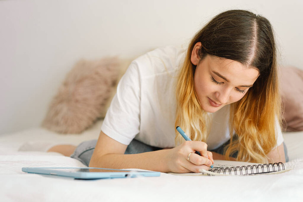 Un'adolescente disegna o fa i compiti in camera da letto. Un adolescente studia a casa. Ritorno a scuola - Foto, immagini