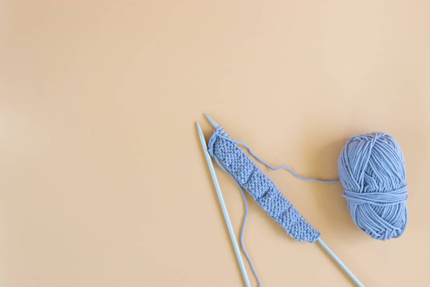 Top view of gray knitting wool and knitting needles on pastel orange background. - Fotografie, Obrázek
