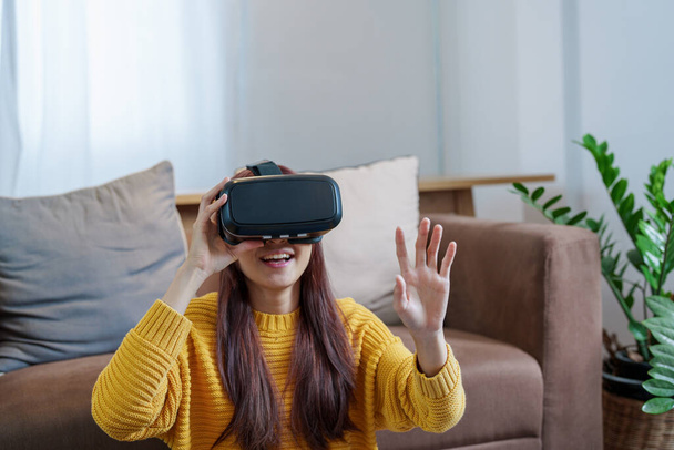 portrait of a young Asian woman using virtual reality simulator headset at home. - Photo, Image