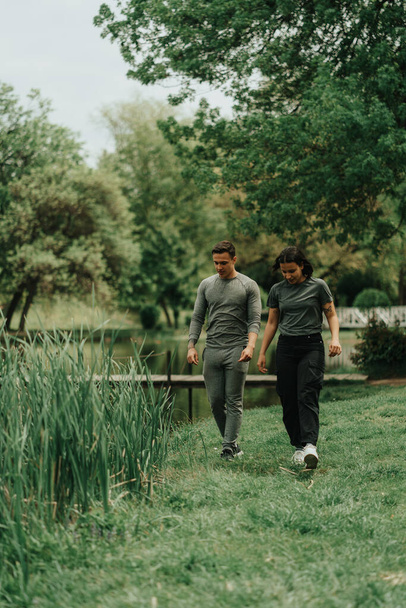 Schönes Sportpaar spaziert durch den Park und sucht etwas auf dem Boden - Foto, Bild