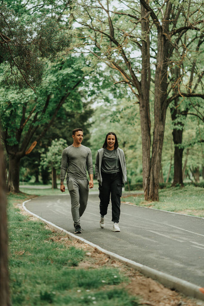 Piękna para rozmawiająca podczas spaceru ścieżką po parku - Zdjęcie, obraz