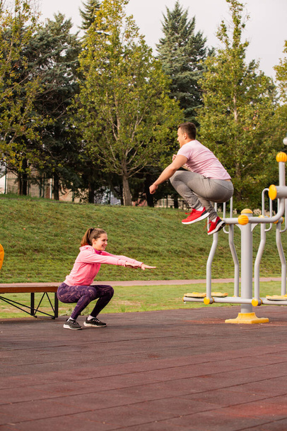 Incrível e lindo casal está fazendo algum exercício de salto juntos no parque enquanto se aquece - Foto, Imagem