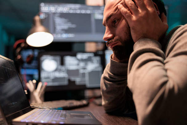Gestresste, traurige Entwickler, die Serverdatenbank programmieren, frustriert über das nächtliche Versagen künstlicher Intelligenz. Überarbeiteter Programmierer, der sich müde fühlt, arbeitet mit HTML-Code, Arbeitsbelastung. - Foto, Bild