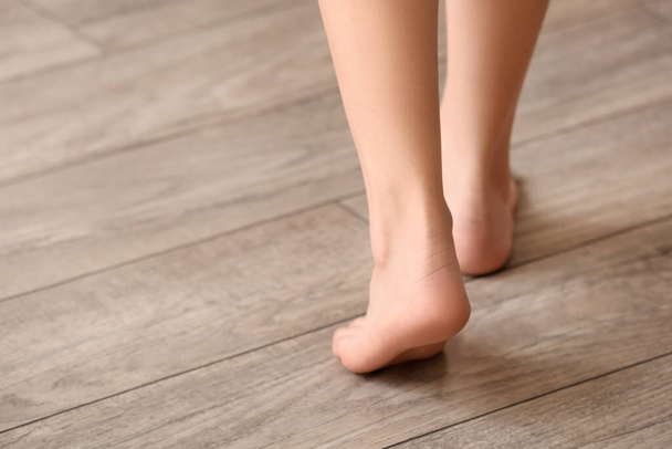 Barefoot woman walking on wooden floor at home, closeup - Zdjęcie, obraz