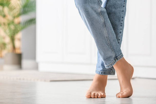 Barefoot woman in jeans on floor, closeup - 写真・画像