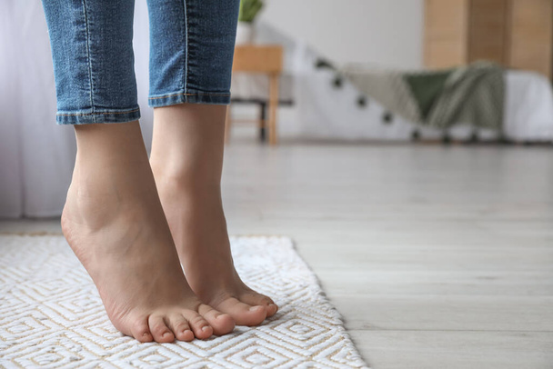 Female bare feet on rug in room, closeup - Фото, изображение