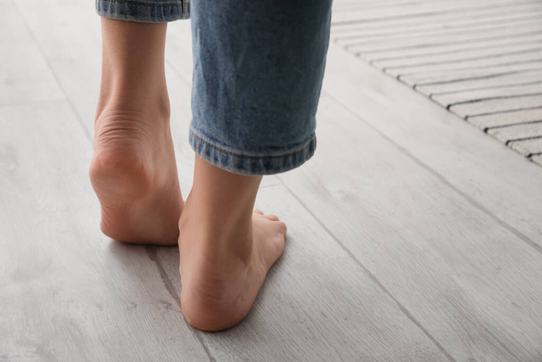 Γυναικεία γυμνά πόδια σε ανοιχτό ξύλινο πάτωμα, κοντινό πλάνο - Φωτογραφία, εικόνα
