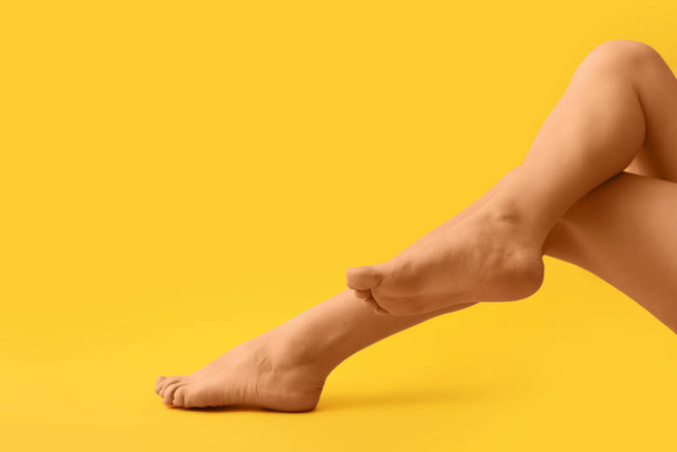 Female barefoot legs on yellow background - Foto, afbeelding
