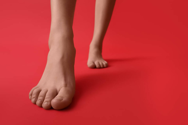 赤い背景の女性の裸の足、クローズアップ - 写真・画像