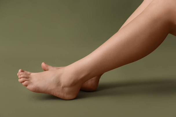 Vrouwelijke blootsvoets benen op kleur achtergrond - Foto, afbeelding