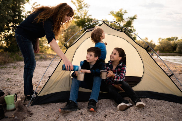 Glückliche Familie auf dem Zeltplatz im Wald. Camping-, Wander- und Personenkonzept - Foto, Bild