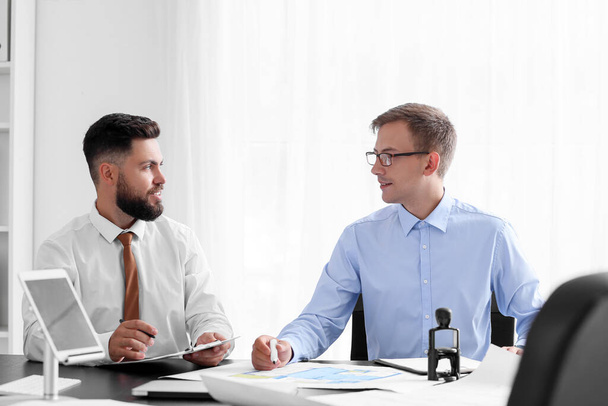 Male bank manager working with his colleague at table in office - Foto, Imagem