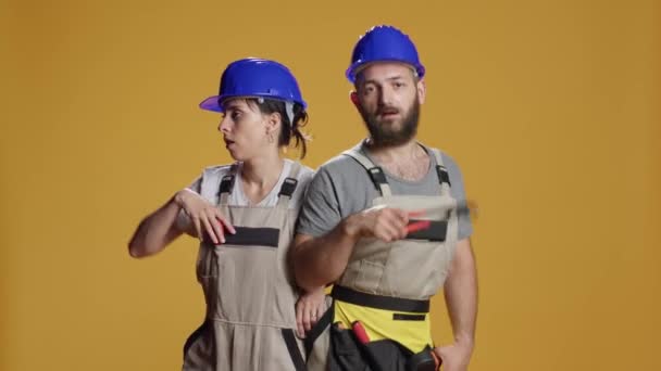 Happy constructors dancing and singing in studio, having overalls and helmets. Doing dance moves and having fun before working on construction site, funny mechanics enjoying music. - Footage, Video