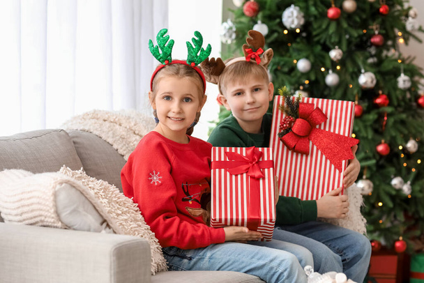 Crianças pequenas felizes em chifres de rena com presentes de Natal em casa - Foto, Imagem