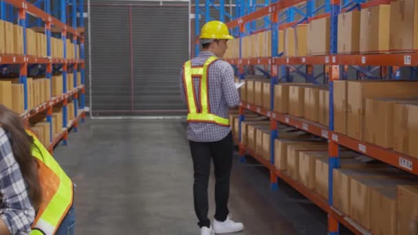 Young man and woman worker check stock and inspection with document on clipboard in the warehouse at factory, worker working at storehouse, logistic and cargo, shipping and distribution. - Filmati, video