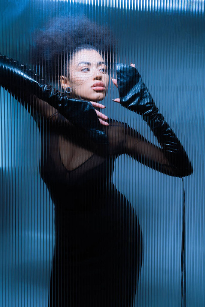 young african american woman in black veil and sexy outfit looking away through ruffled glass - Fotoğraf, Görsel