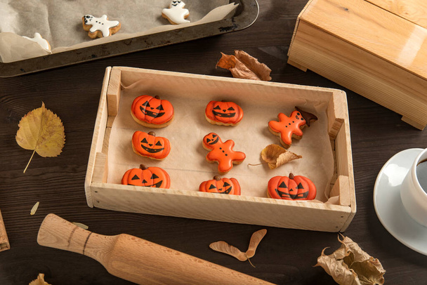 カボチャの形のオレンジジンジャーブレッド。ハロウィンのお菓子は木製のトレイにあります。テーブルの上のおいしいクッキー。トップ表示. - 写真・画像