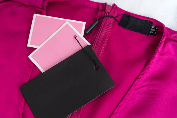 Vestido de fúcsia rosado ou blusa com etiquetas pretas vazias. Roupas femininas de seda. Marca falsa. - Foto, Imagem