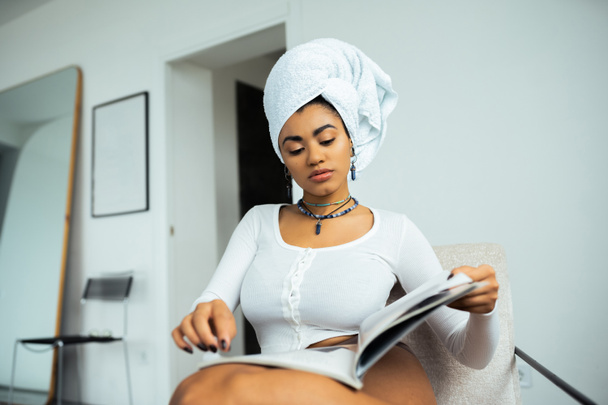jolie femme afro-américaine avec serviette sur la tête lecture magazine à la maison - Photo, image