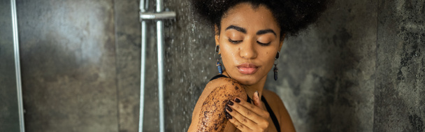 Young african american woman massaging body with scrub in shower cabin, banner  - Fotó, kép